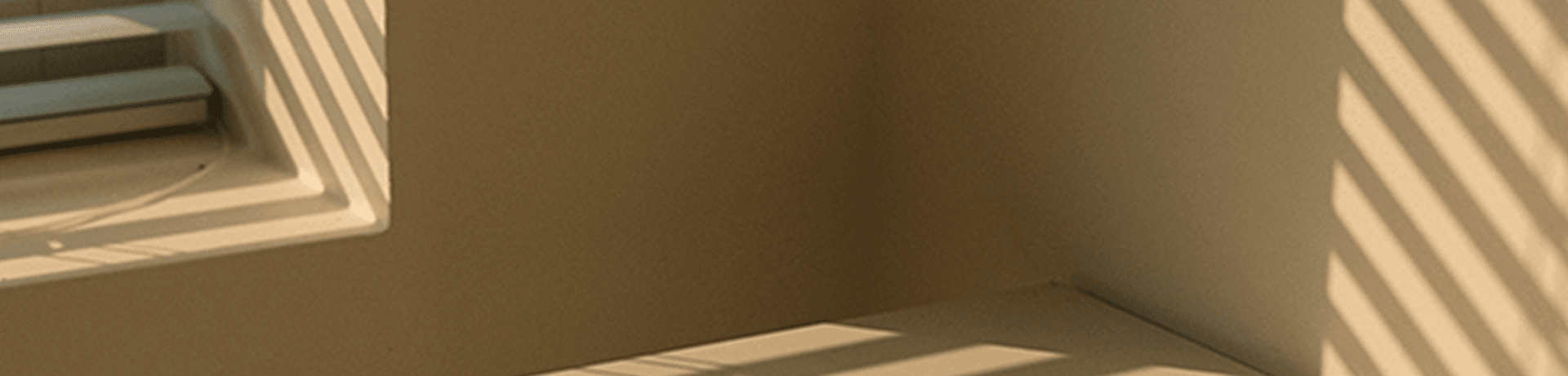 A room corner with shadows from window blinds creating a calm atmosphere